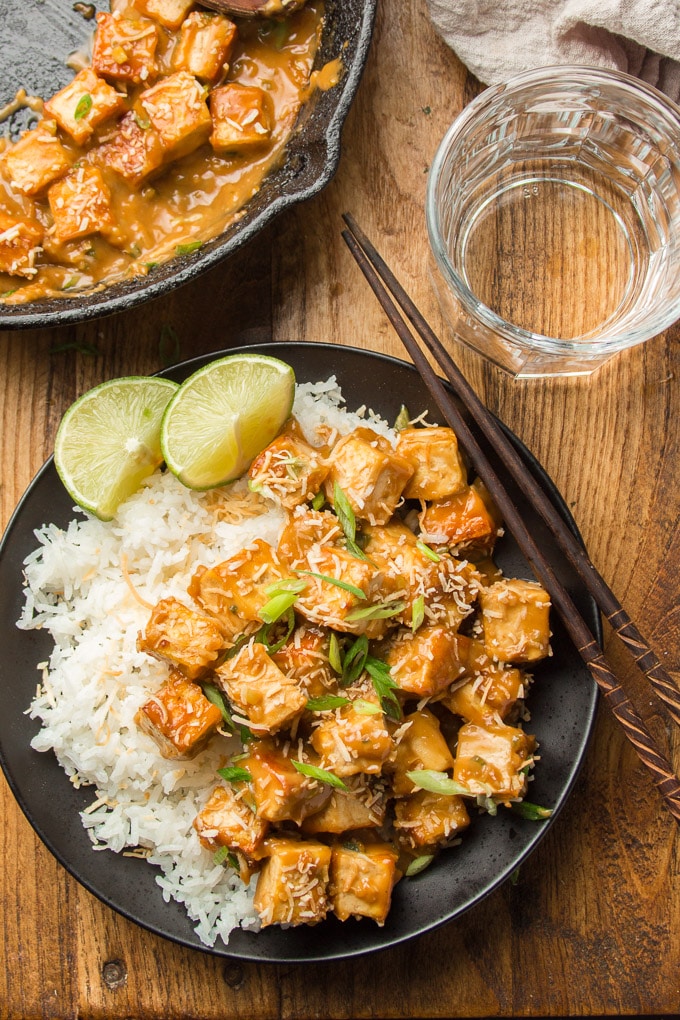 Wooden Table Set with Plate of Sweet & Sticky Coconut Tofu, Skillet, and Water Glass