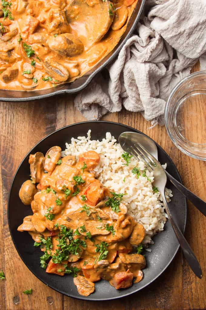 Wooden Table Set with Skillet, Water Glass, and Plate of Vegan Mushroom Paprikash with Rice