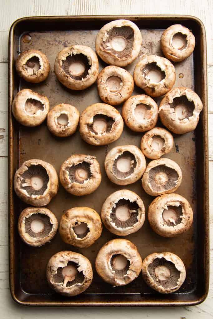 Cremini mushroom caps on a baking sheet.