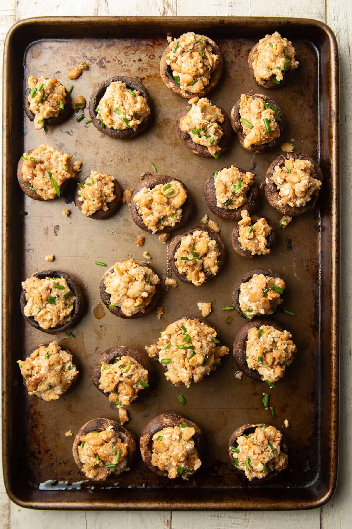 Baking sheet with unbaked vegan stuffed mushrooms on it.