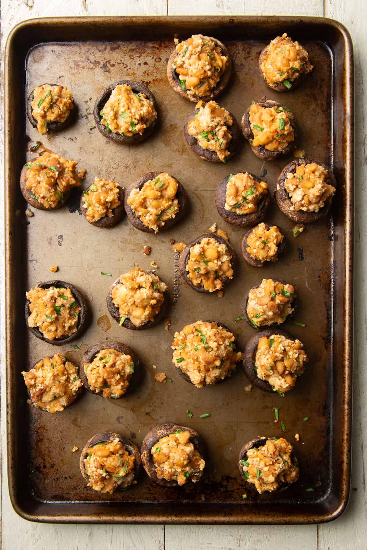 Baking sheet with vegan stuffed mushrooms on it.