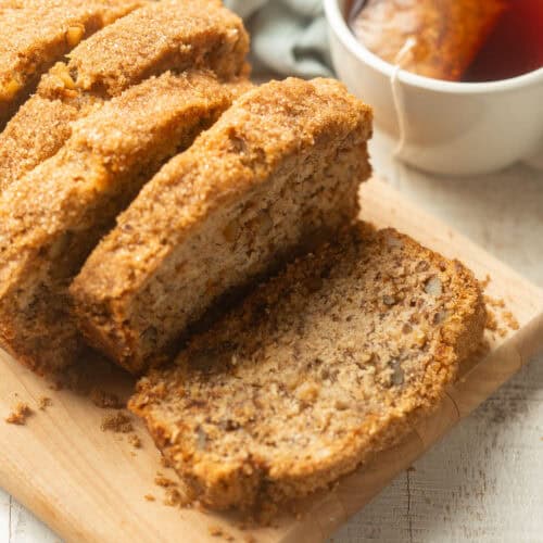 Sliced loaf of Vegan Banana Bread with a cup of tea in the background.