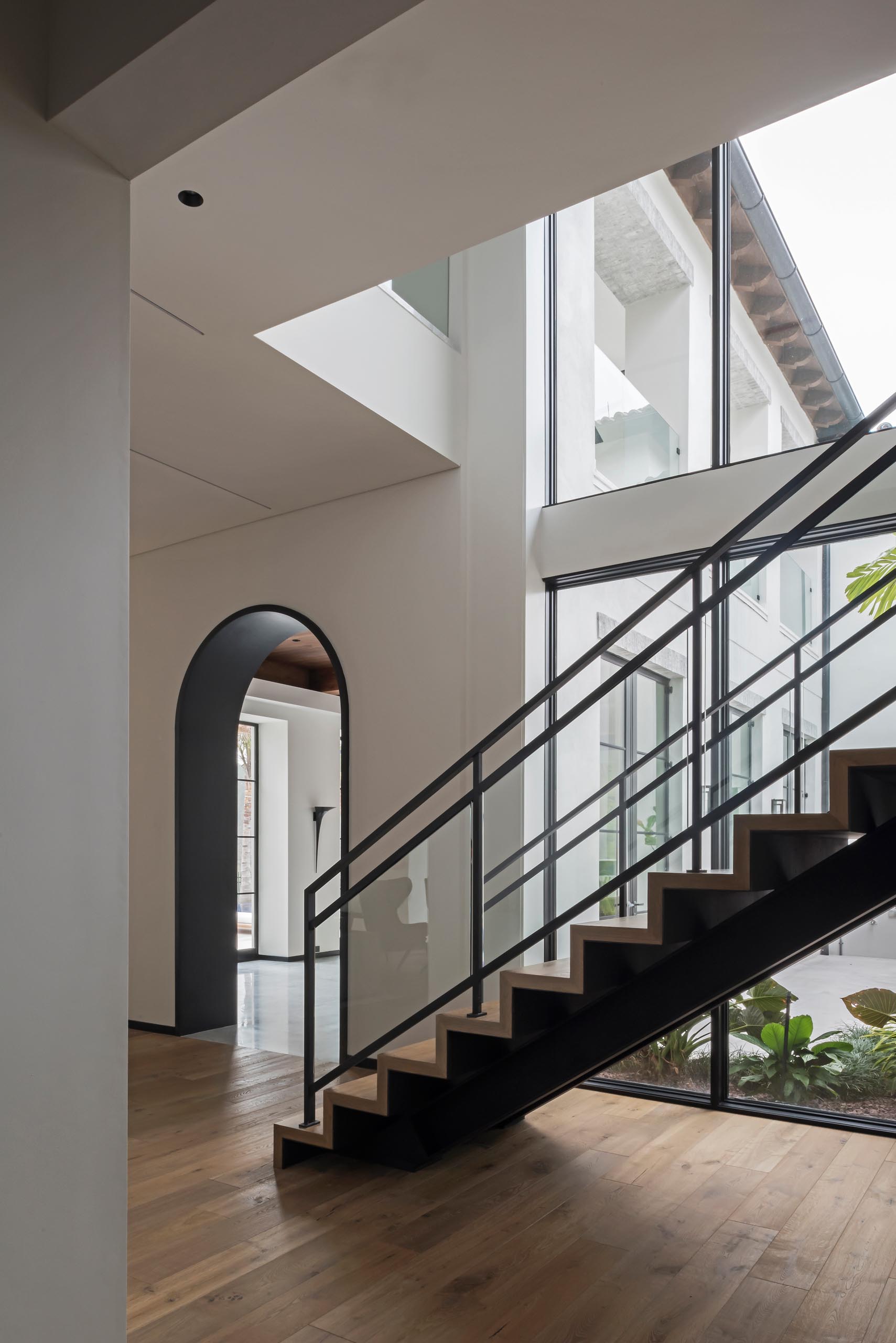 The black lined arches meet with the trim at the bottom of the walls, which wraps around the rooms, as well as the black window frames and stairs structure.