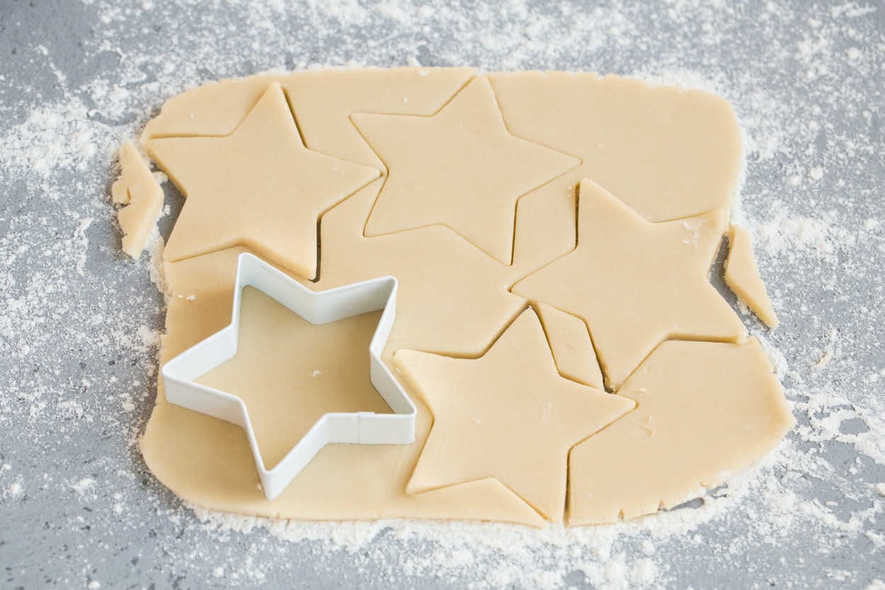 Cutting star shapes from cookie dough for stained glass cookies.