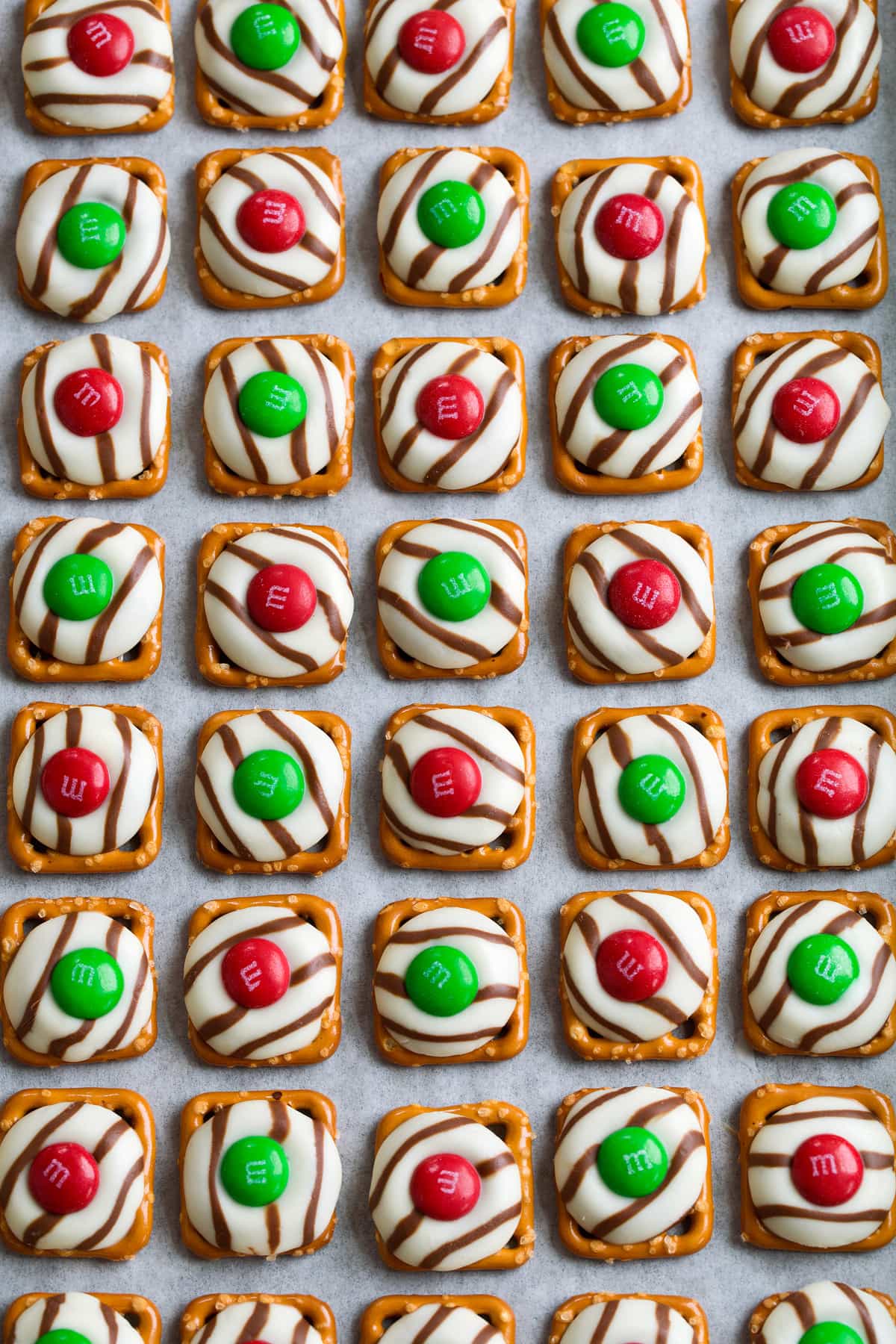 Pretzel M&M Hugs in rows on parchment paper lined baking sheet.