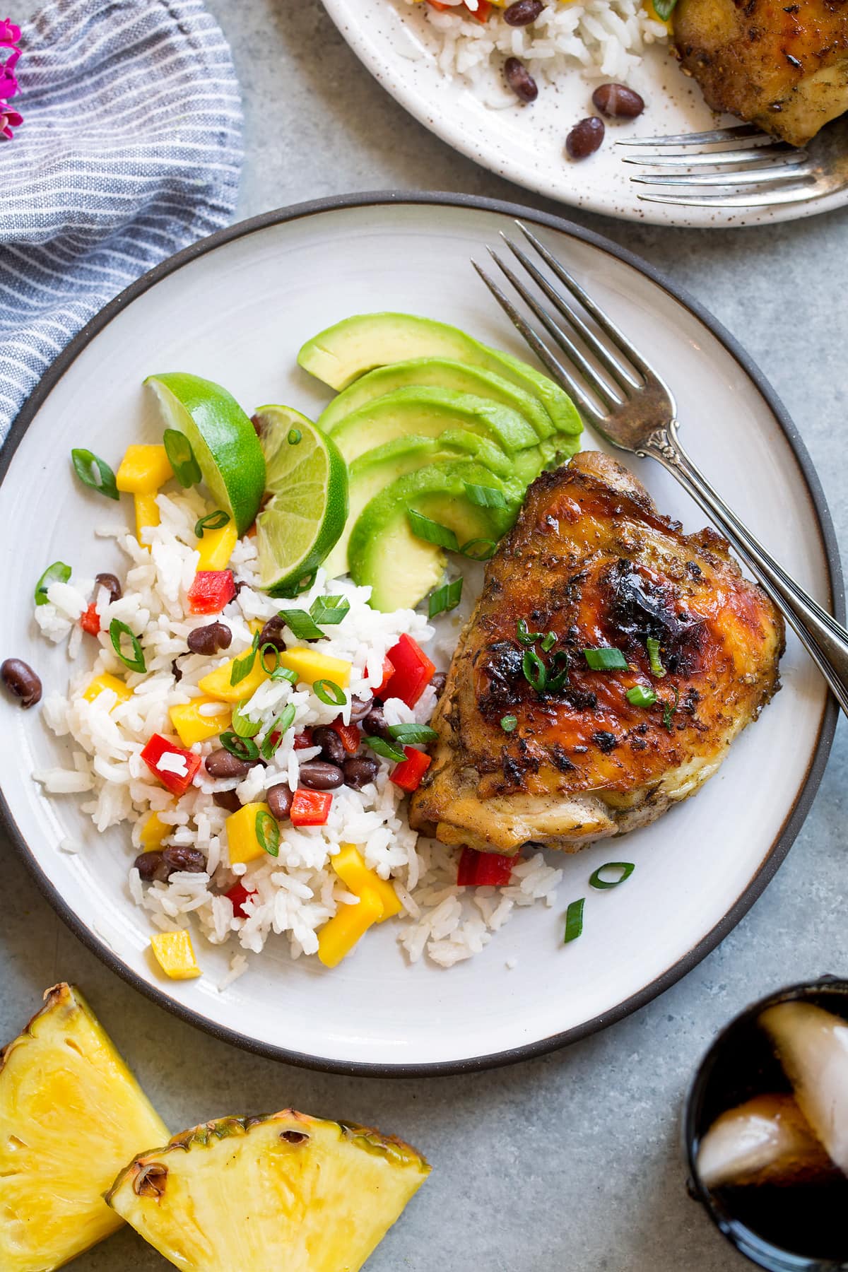 Single piece of jerk chicken with a side of coconut rice and avocado.