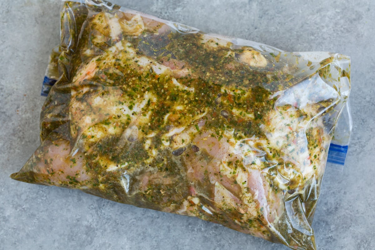 Soaking chicken pieces in a resealable bag with marinade.