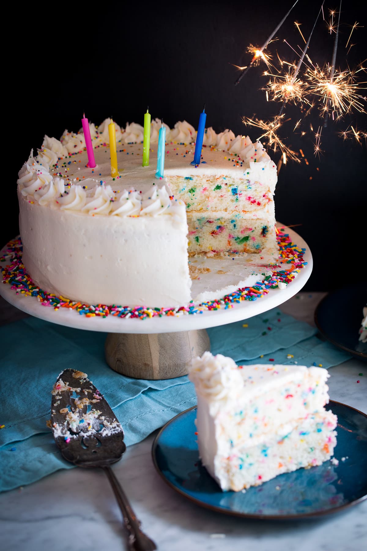 Birthday cake topped with candles and sparklers to the side.