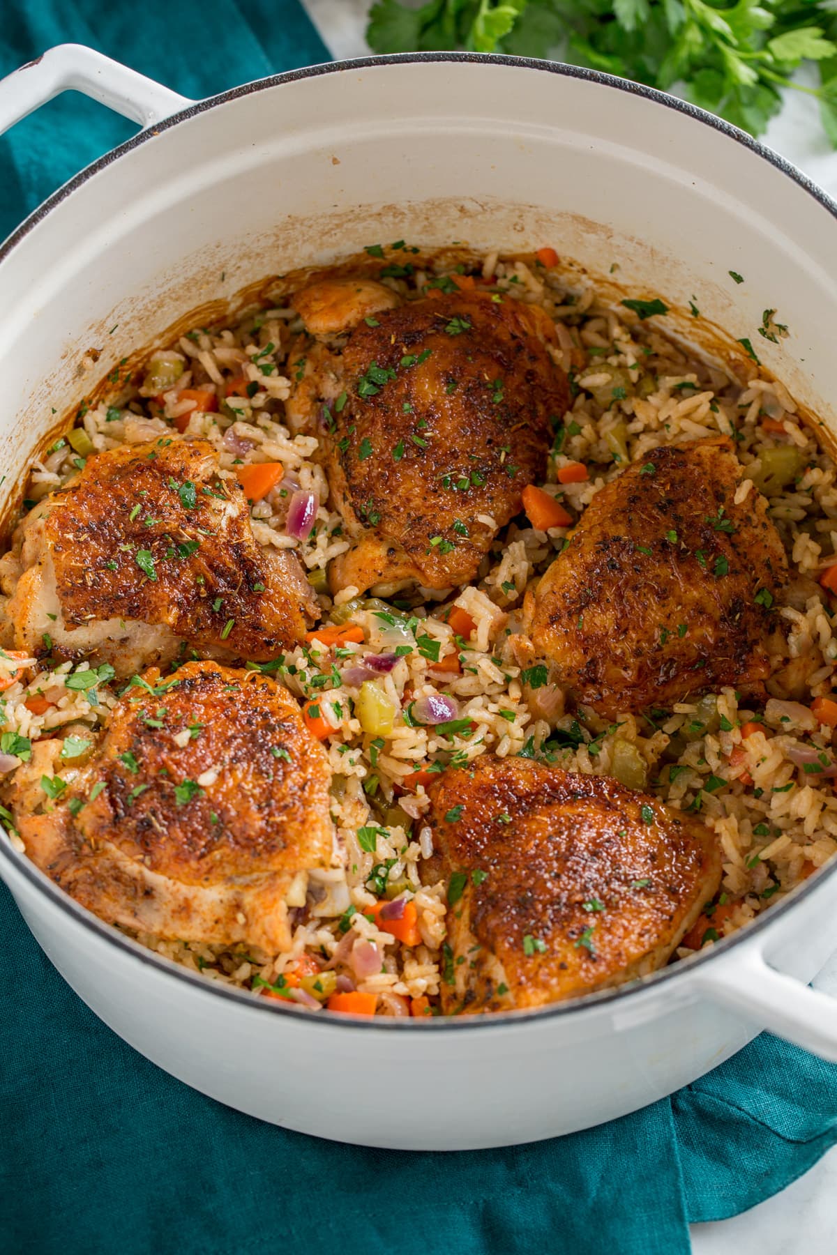 Chicken and rice in a white pot set over a turquoise cloth.