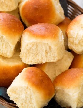 Close up photo of homemade dinner roll showing soft and fluffy texture and golden brown tops.