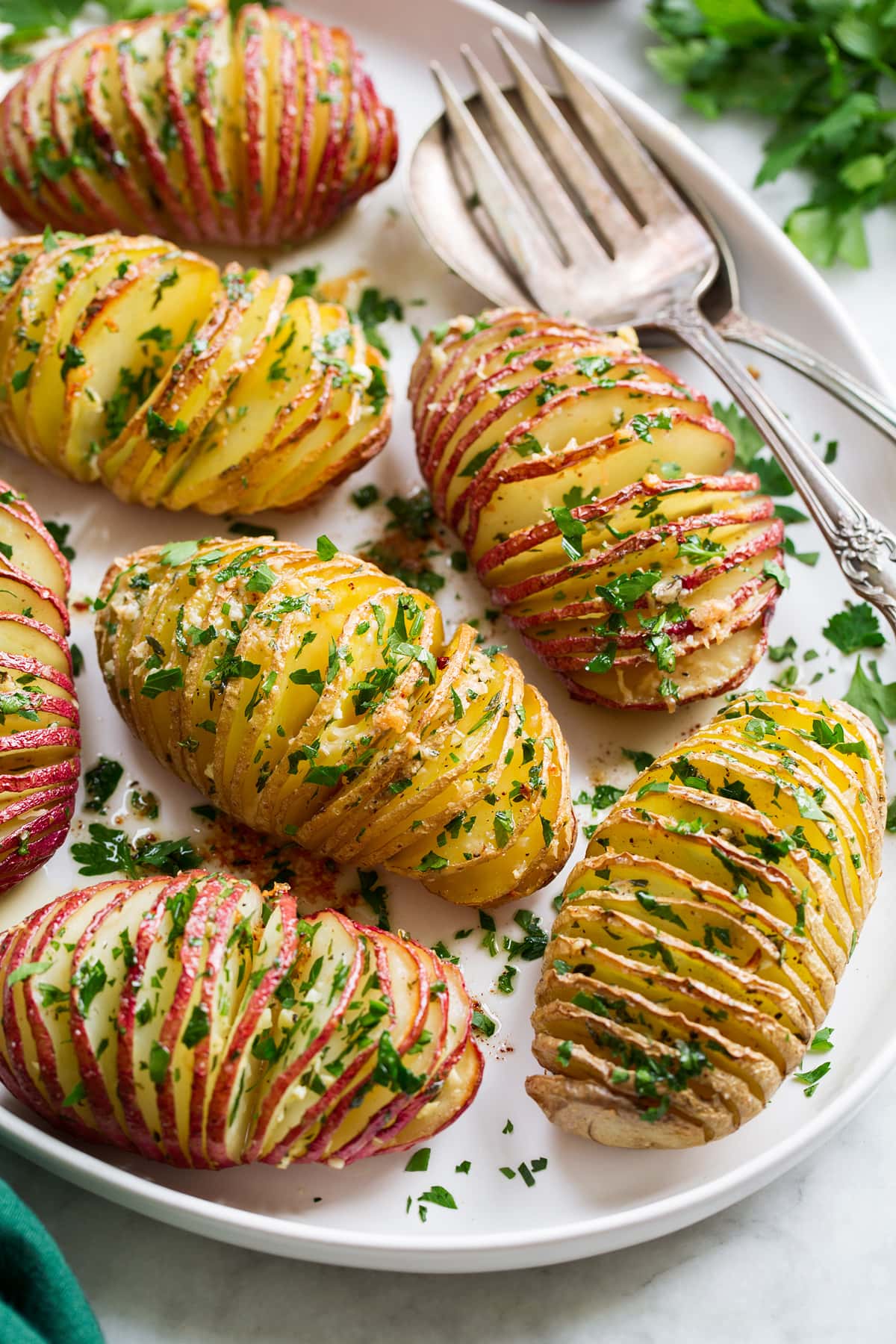 Hasselback Potatoes shown sliced with parmesan and parsley on top.