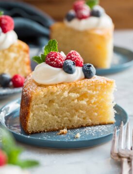 Slice of yogurt cake shown close up with yogurt and berries on top.