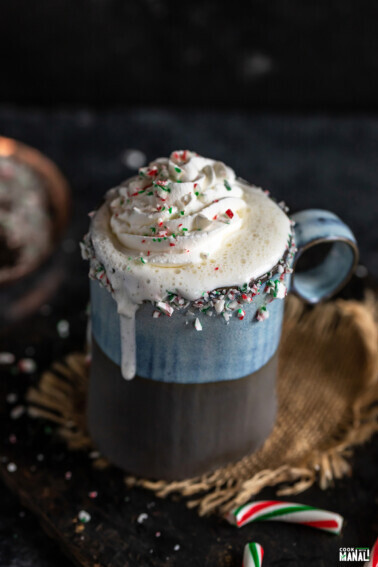 white hot chocolate dripping from the sides of the mug and topped with crushed candy cane