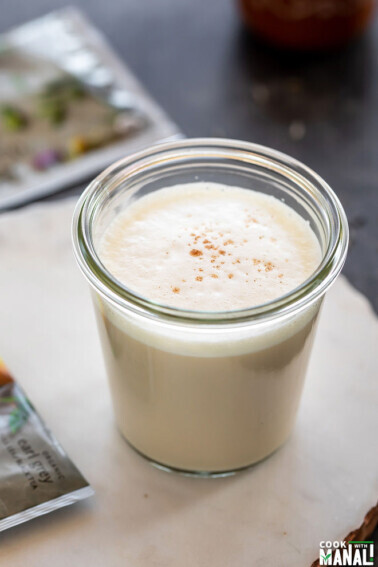 london fog tea latte served in a glass jar with sachet of tea bag lying in the background and one on the side