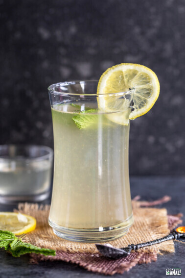 glass of lemonade topped with mint leaves and lemon