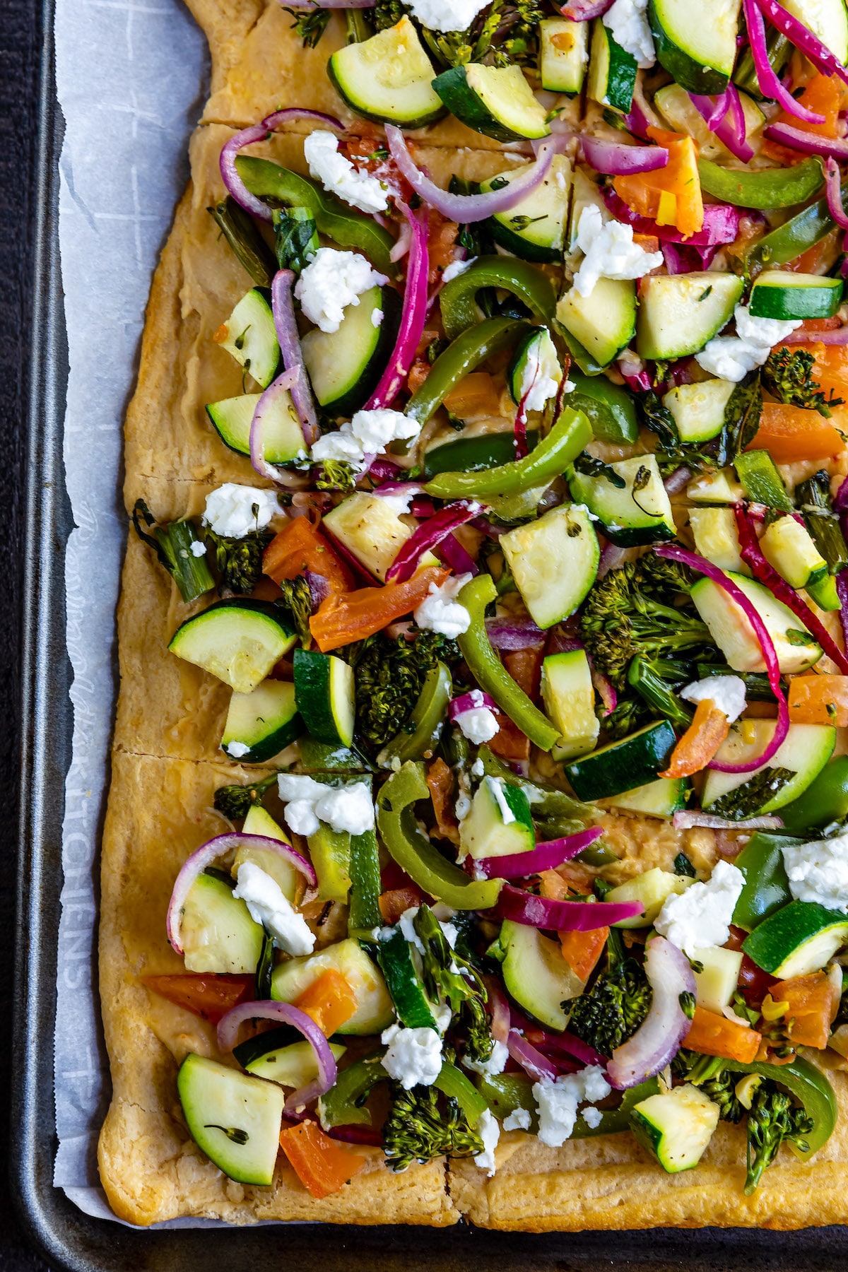 hummus pizza with vegetables on top of the thin crust