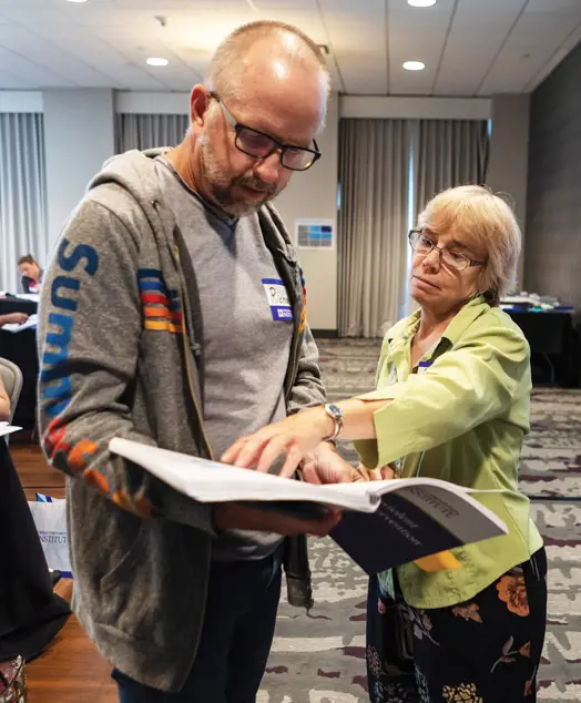 A woman pointing out something in a CPI workbook to a man.