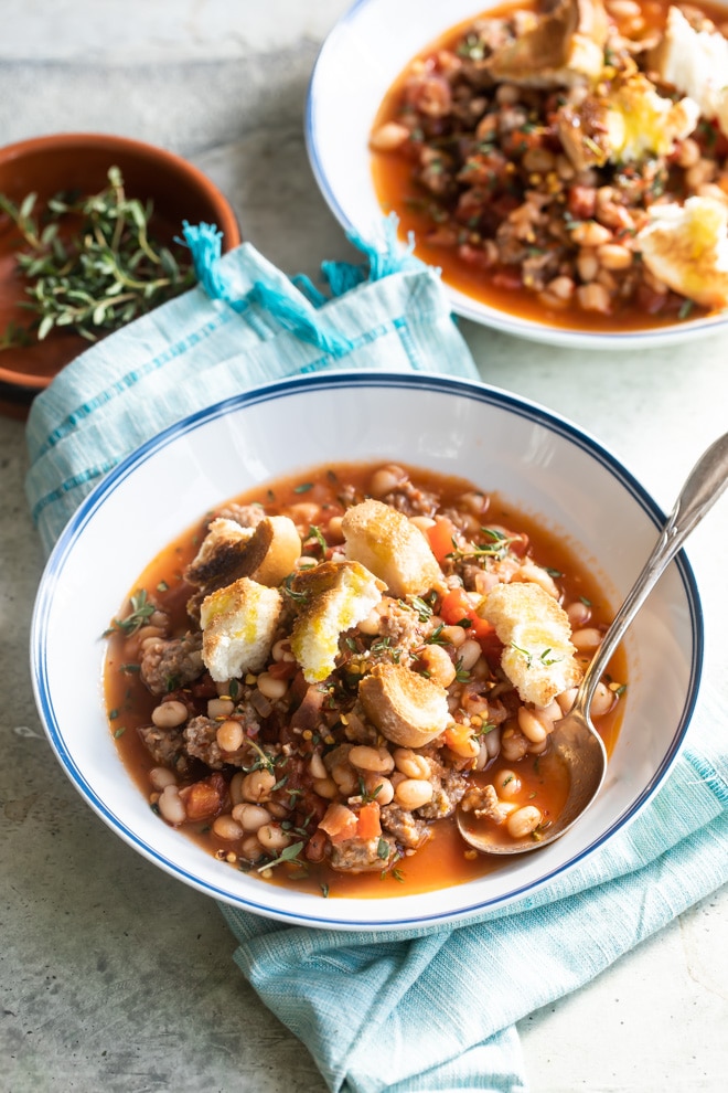 Sausage and bean stew in white bowls.