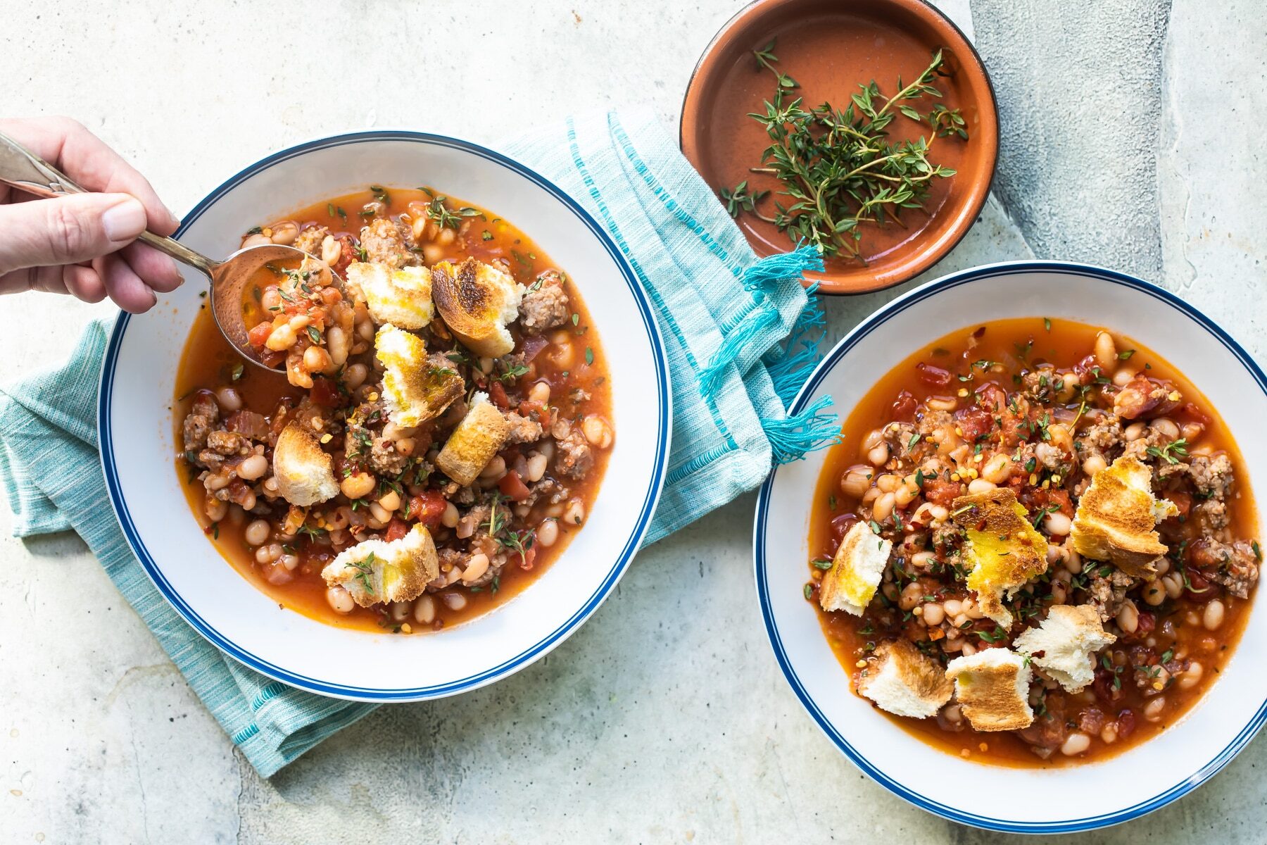 Sausage and bean stew in a white bowl.