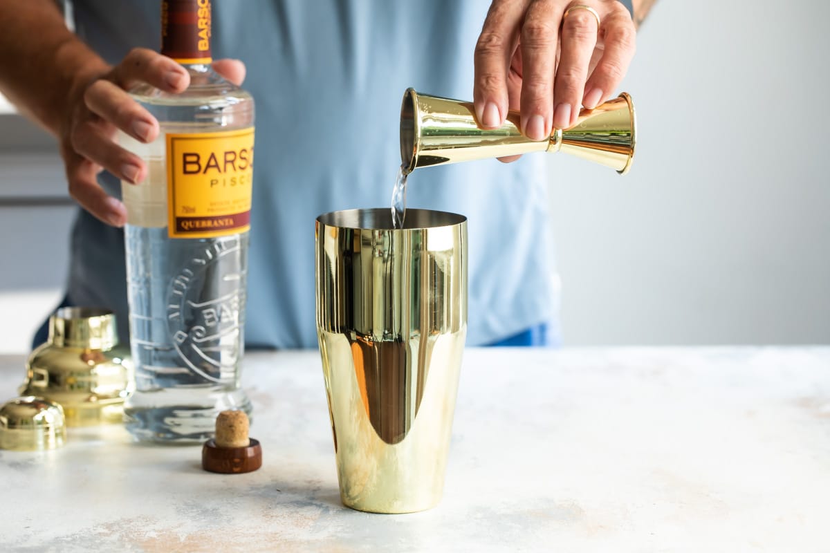 Mixing a pisco sour in a cocktail shaker.