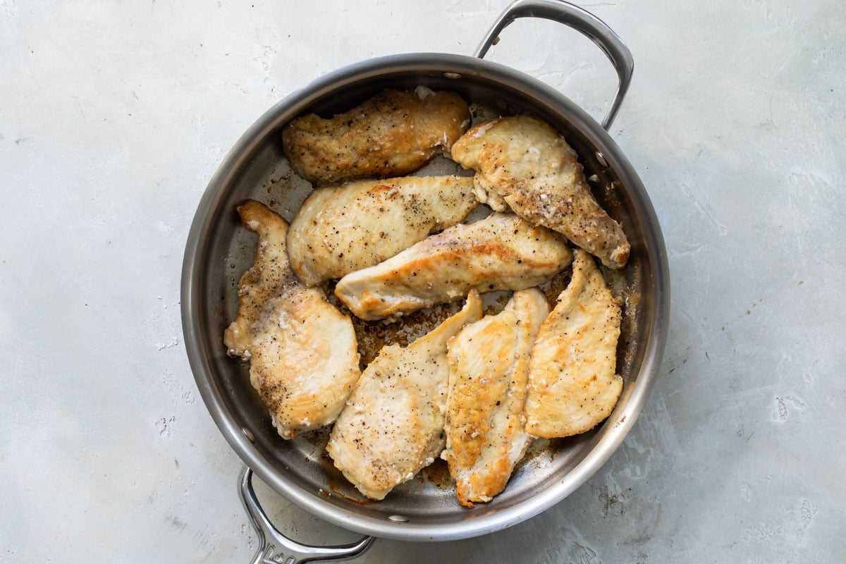 Chicken scallopini in a silver skillet.