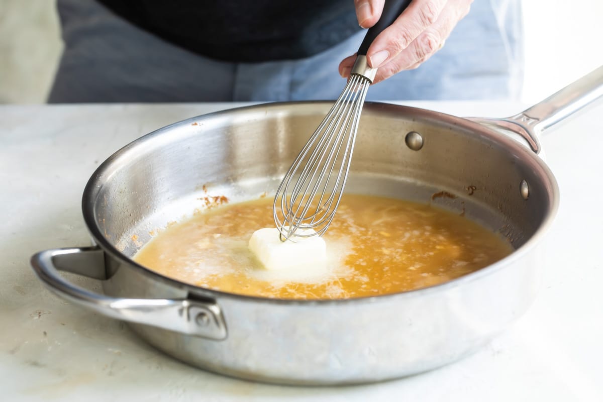 Chicken scallopini sauce being made in a silver skillet.