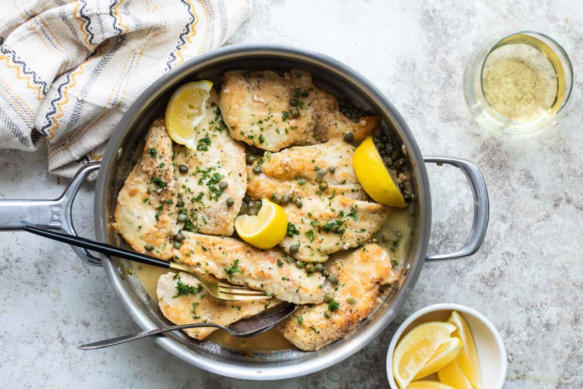 Chicken scallopini in a silver skillet.