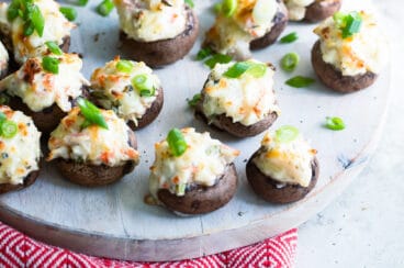 Crab stuffed mushrooms on a wooden platter.