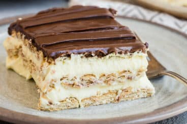 Slices of no-bake Chocolate Eclair Cake on white plates with forks.