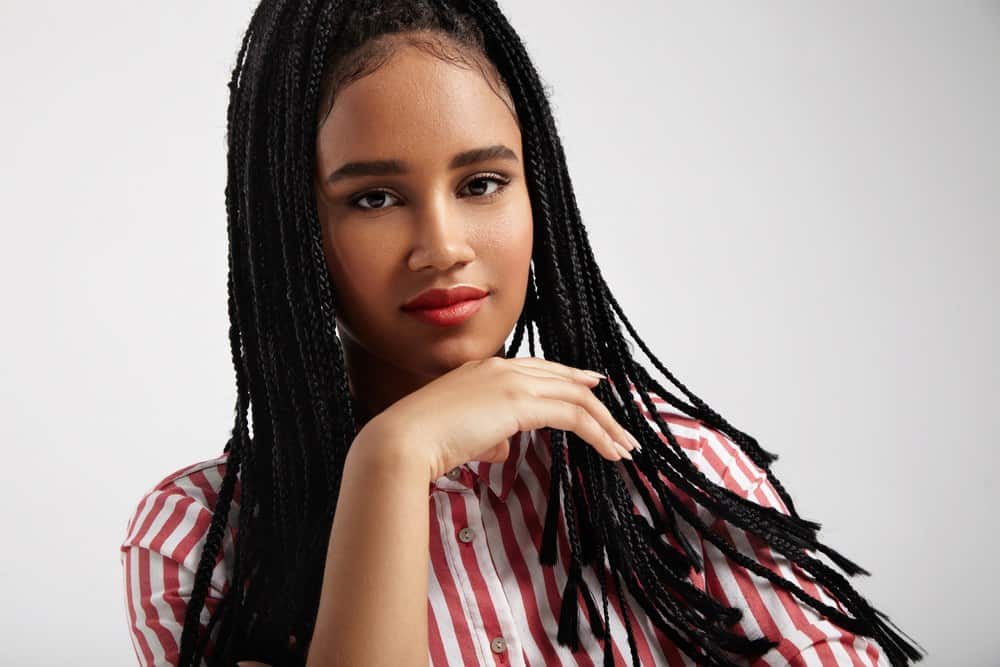 Black woman wears red shirt in rays and braids.