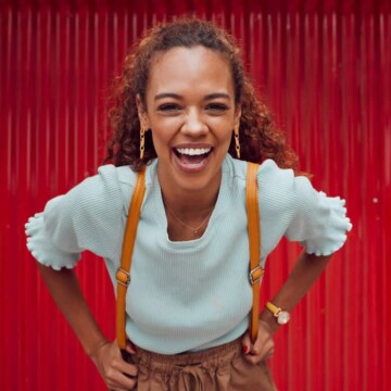 A cute black girl with natural curls on a type 3 hair texture styled with natural oils in a loose ponytail hairstyle that's perfect for her greasy hair.