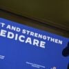 President Joe Biden speaks while standing next to a banner.