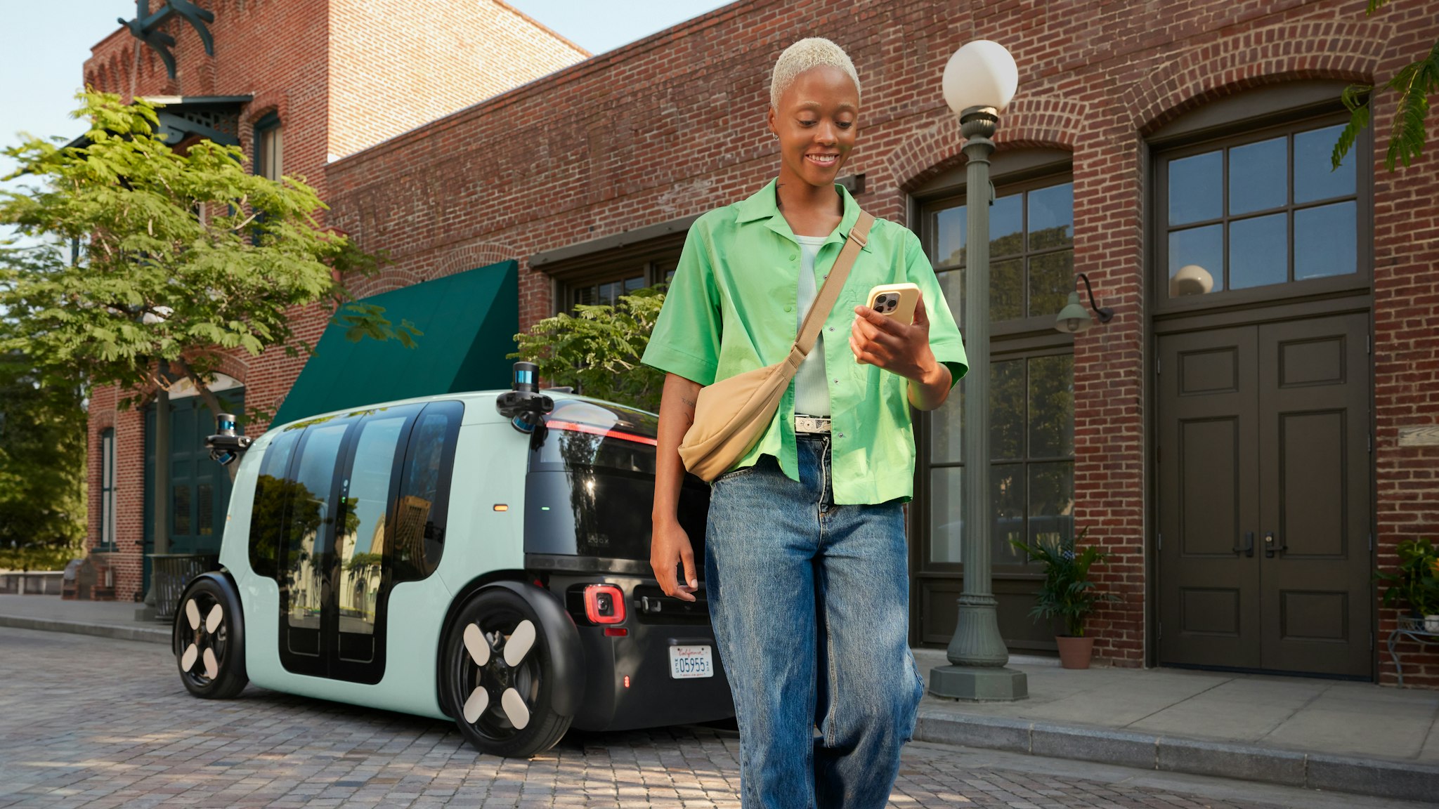 A passenger walks away from a Zoox vehicle while using their phone