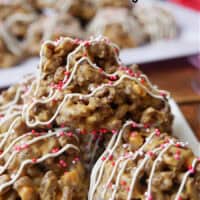 A white plate with three peanut butter butterscotch chocolate crispies on it that are drizzled with white chocolate.