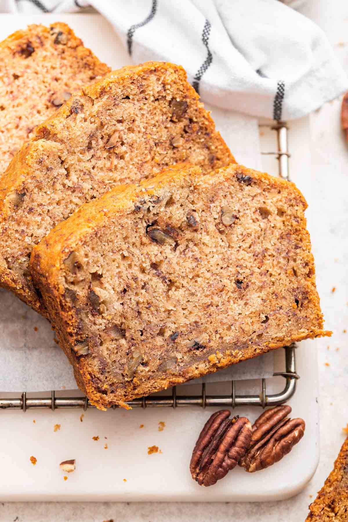 Three slices of eggless banana bread with pecans on the side.