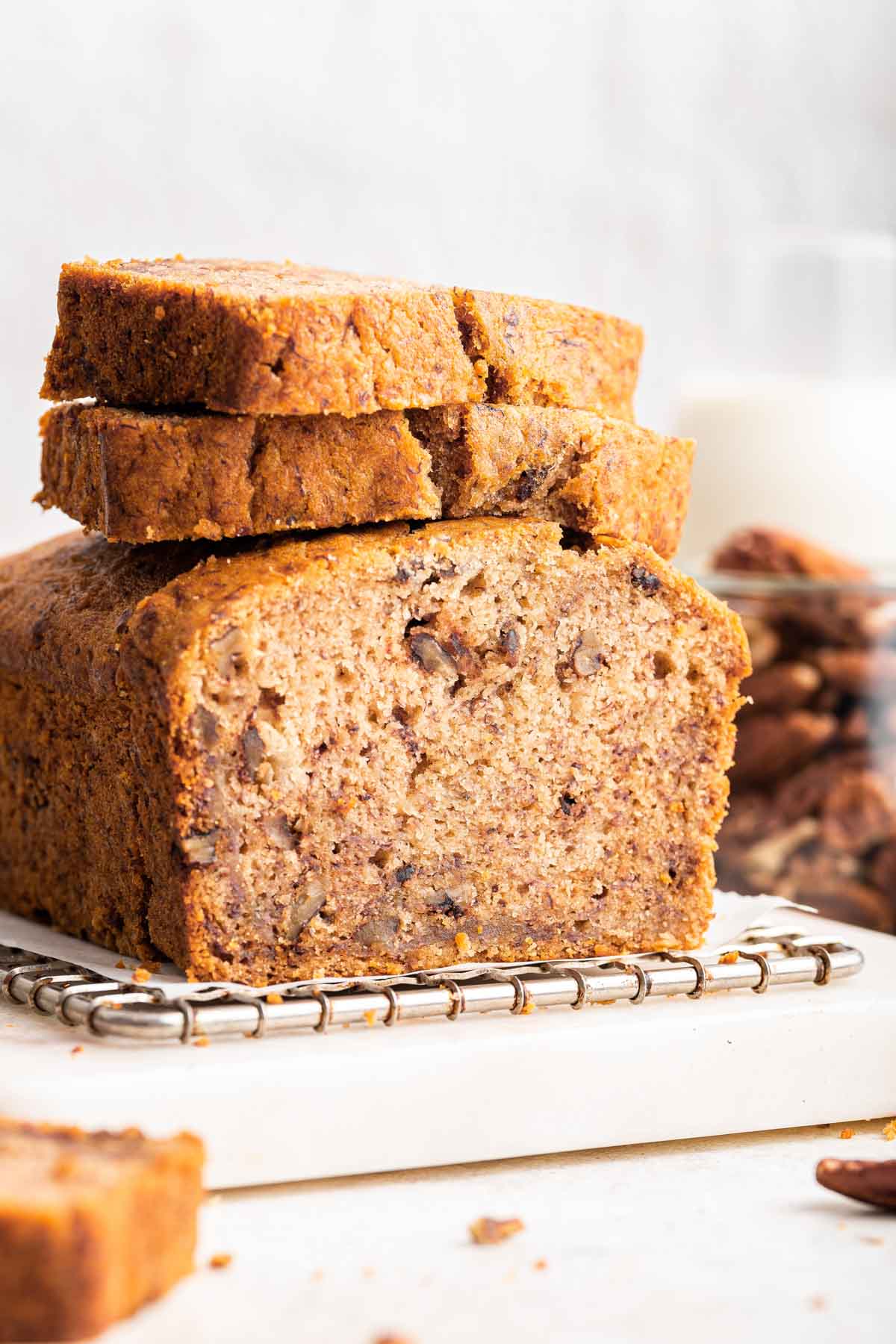 Loaf of eggless banana bread sliced with two slices on top.