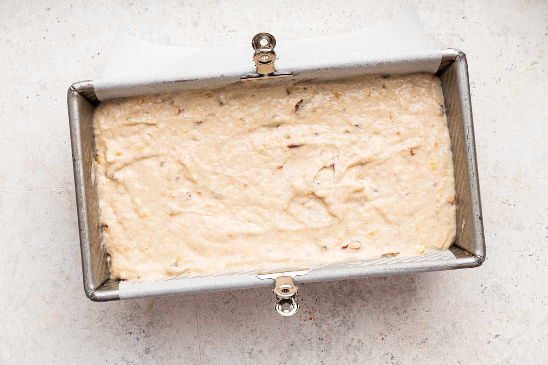 Pale yellow batter in a bread loaf pan.