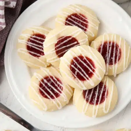 Top view of plate of raspberry thumbprint cookies with icing drizzle.