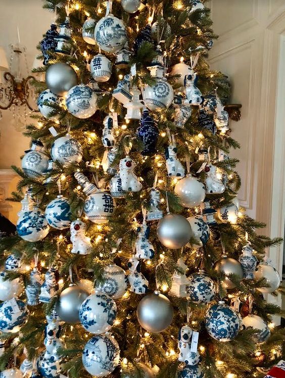 a Christmas tree decorated with lights, blue and white plus silver ornaments, ribbons and porcelain pieces is lovely