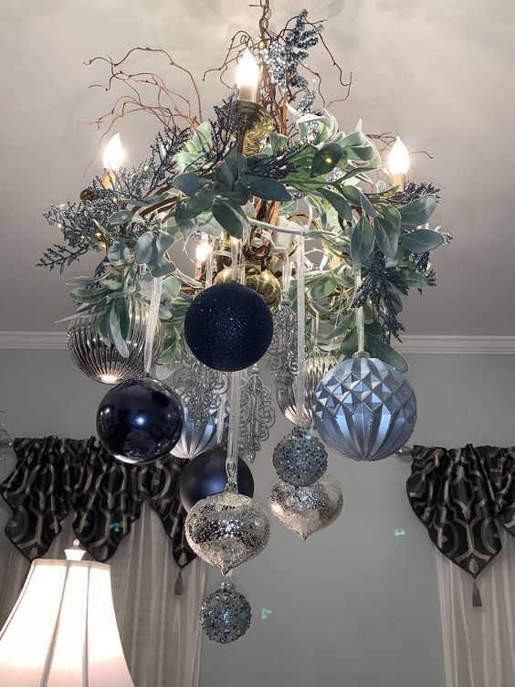 a beautiful Christmas chandelier of navy, light blue and silver ornaments, frozen branches, twigs and candles is wow