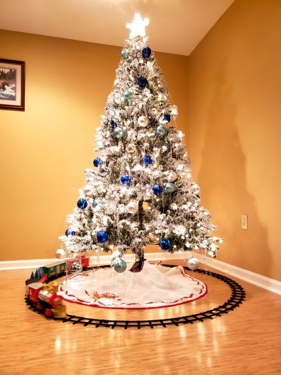 a flocked Christmas tree with lights, silver, navy and light blue ornaments is very beautiful, bold and shiny and looks amazing