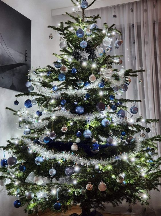 a shining Christmas tree with lights, blue, navy and silver ornaments and stars is a beautiful and chic idea