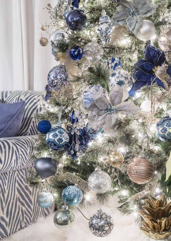 a silver Christmas tree with silver, light blue and navy ornaments, fabric blooms and ribbons is a very chic and glam idea