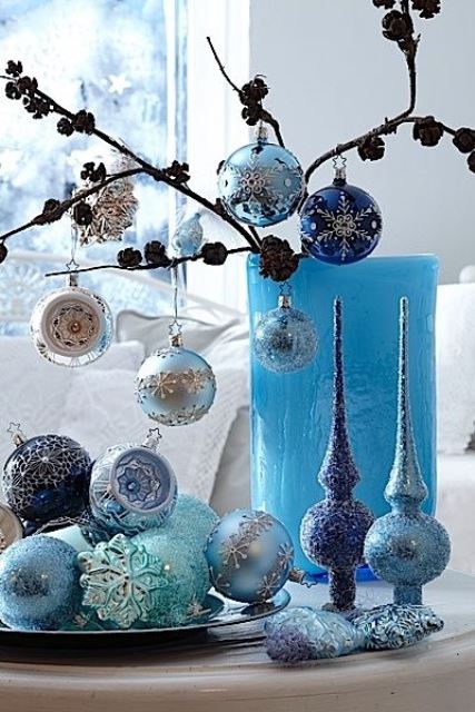 lovely blue and silver Christmas decor with a branch with ornaments, ornaments on the plate and some tree toppers