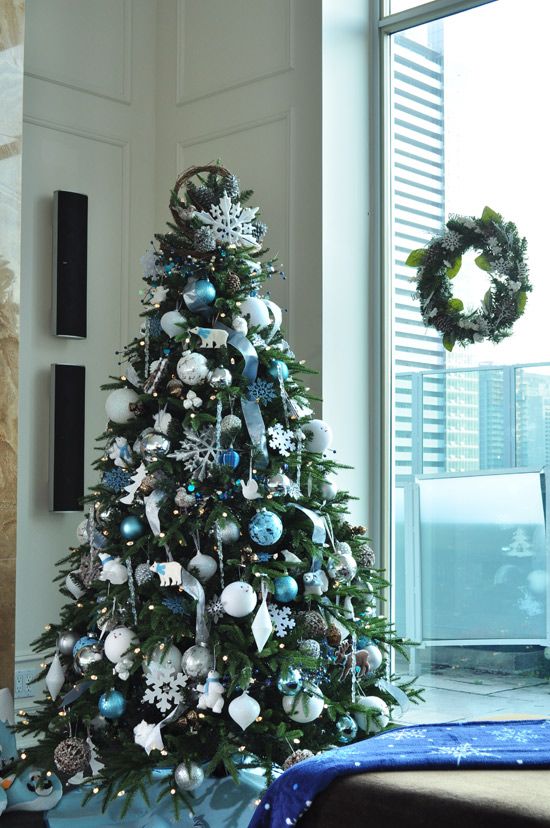 a frozen Christmas tree decorated with blue and silver ornaments, ribbons, snowflakes and other plywood ornaments is a chic and cool idea