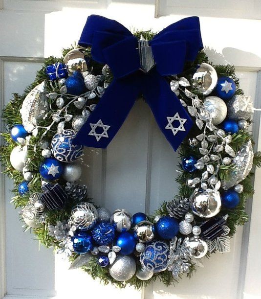 a bright Christmas wreath with bold blue, silver and white oraments and a large navy velvet bow on top is an amazing decoration