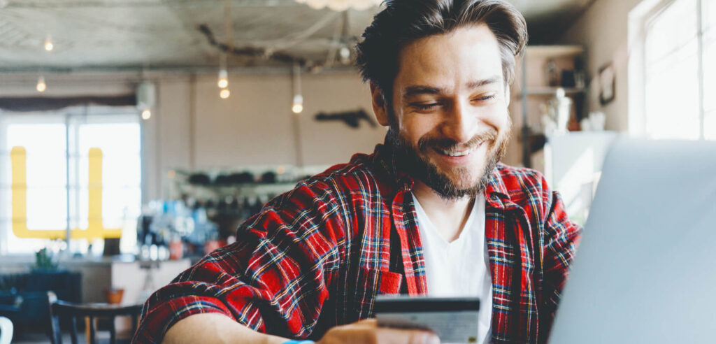 man holding credit card and using laptop