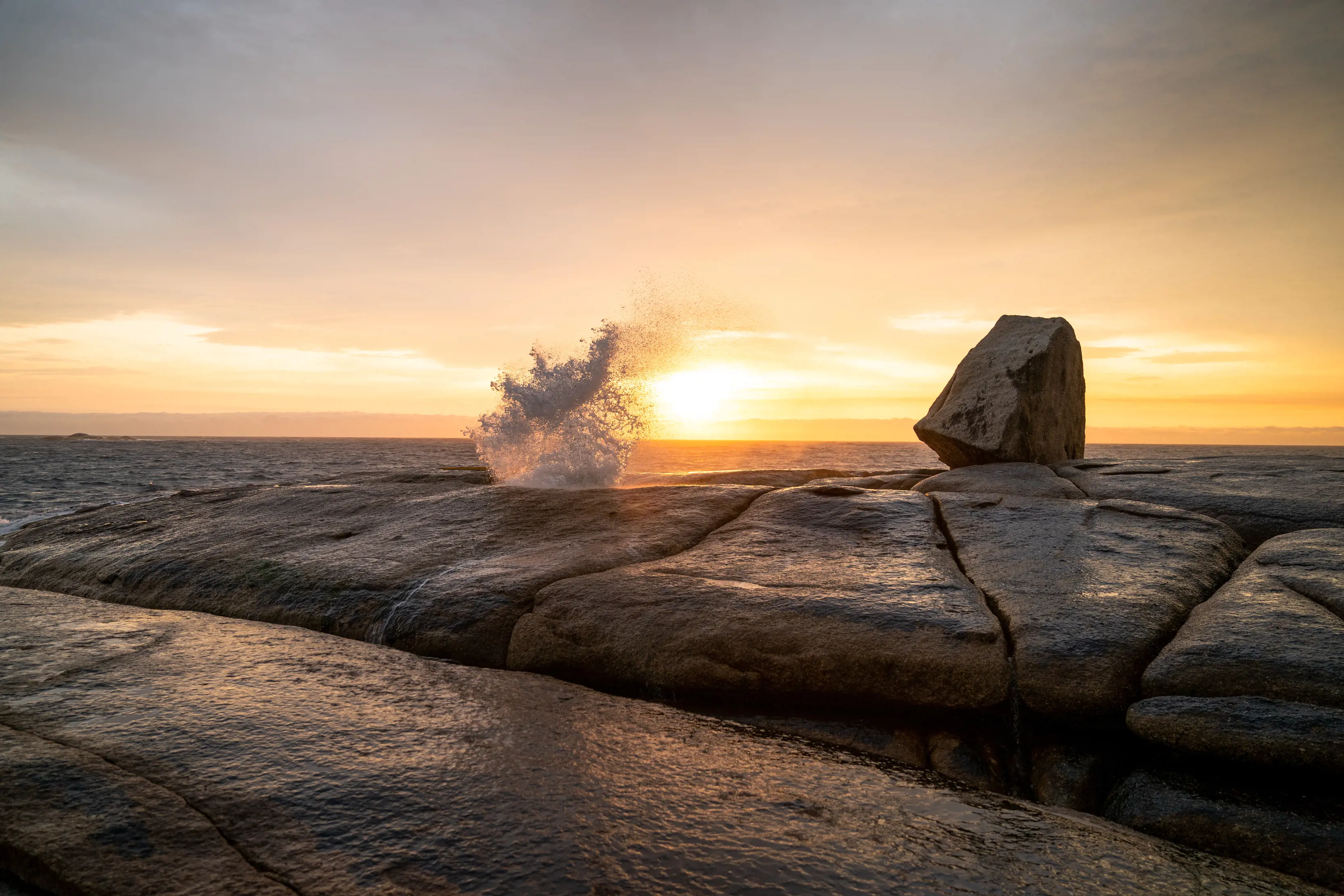 Water spurting from the Bicheno Blowhole. The sun sets in the background.