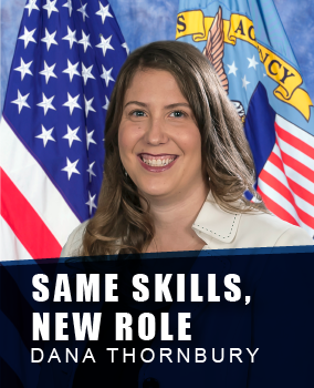 Portrait of a woman smiling, wearing a white blazer, standing in front of the American flag and another official flag in a government setting. Under her photo the banner says "Same Skills New Role, Dana Thornbury".