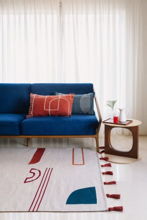 blue sofa in living room with multicolored rug